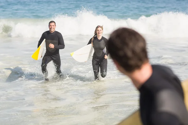 Couple with surfboard running on the beach — Stock Photo, Image