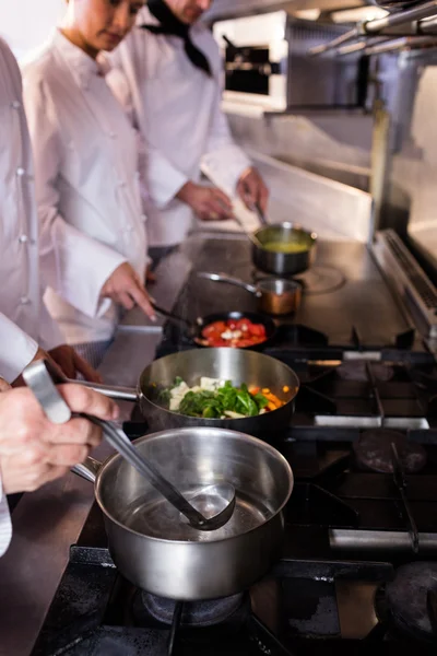 Groep van chef-kok bereiden van voedsel in de keuken — Stockfoto