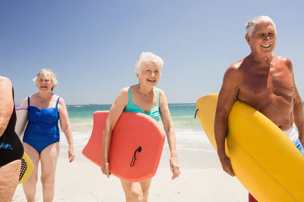 Starszy przyjaciele trzymając deskę surfingową — Zdjęcie stockowe