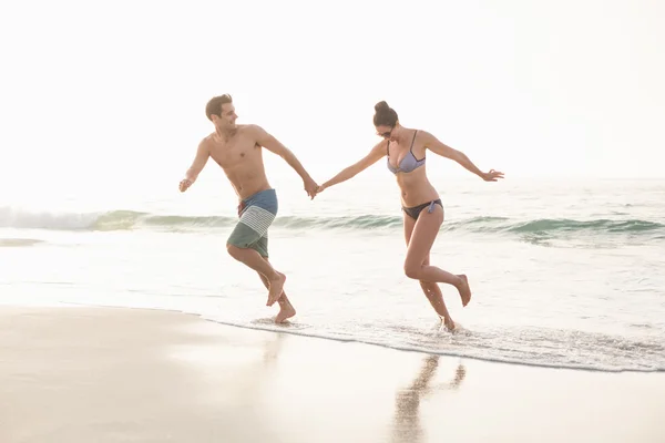 幸福的夫妻在海滩上奔跑 — 图库照片