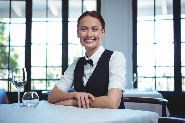 Kelnerka pozowanie i siedzi przy stole — Zdjęcie stockowe