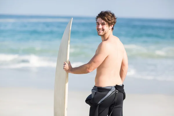 Bonito homem segurando prancha na praia — Fotografia de Stock