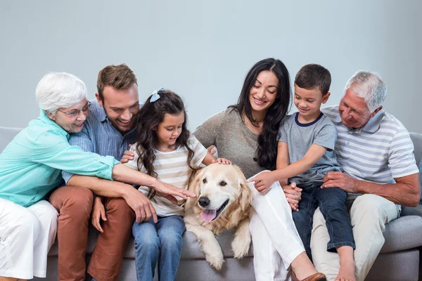 Família sentada no sofá com cão — Fotografia de Stock