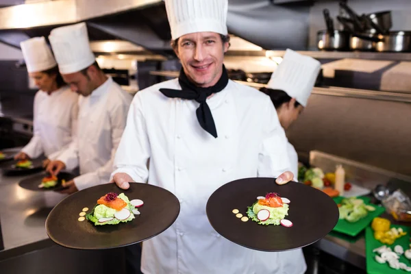 Happy köksmästaren presenterar sin mat tallrikar — Stockfoto