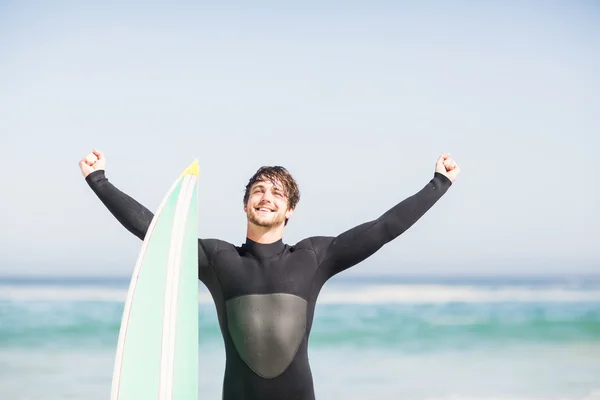 Uomo con tavola da surf in piedi sulla spiaggia — Foto Stock