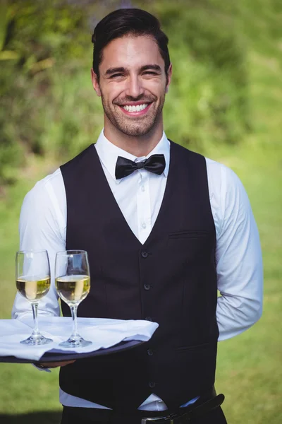 Gutaussehender Kellner mit einem Tablett mit zwei Gläsern Wein — Stockfoto