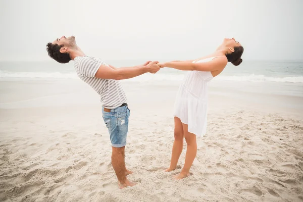 Gelukkige paar bedrijf handen op het strand — Stockfoto