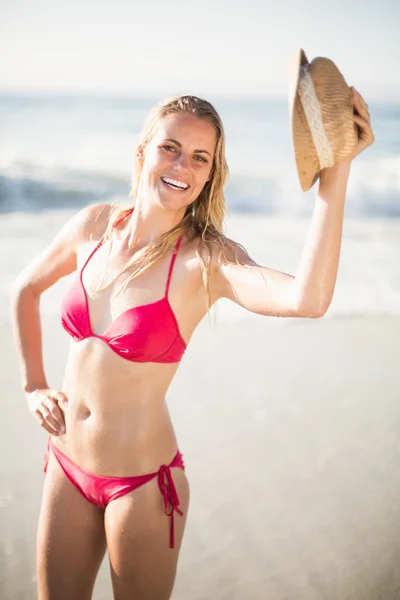 Mulher de biquíni segurando um chapéu na praia — Fotografia de Stock