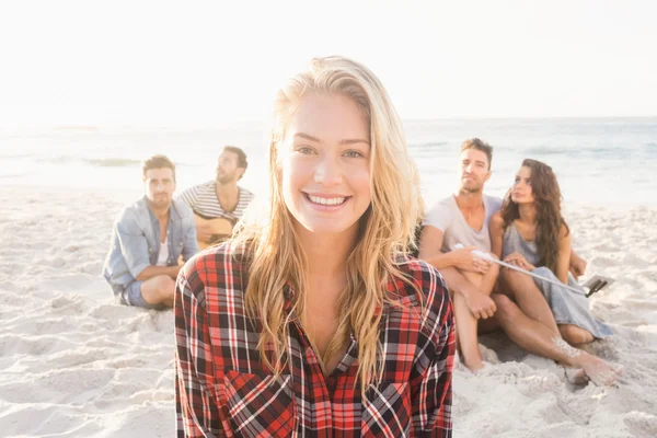 Amigos sorridentes sentados na areia — Fotografia de Stock