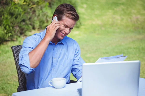 Knappe zakenman aan de telefoon die een document leest — Stockfoto