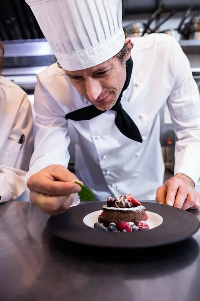 Chef garnishing dessert with mint leaf — Stock Photo, Image
