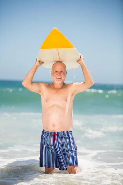 Uomo anziano che trasporta tavola da surf — Foto Stock