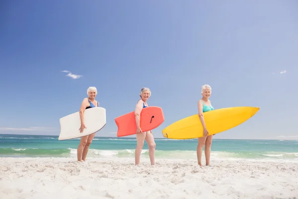 Друзі старшої жінки тримають дошку для серфінгу — стокове фото
