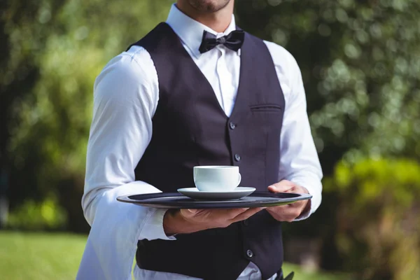 Garçom bonito segurando uma bandeja com xícara de café — Fotografia de Stock