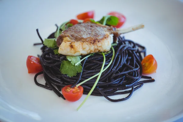 Squid ink spaghetti dish with basil — Stock Photo, Image