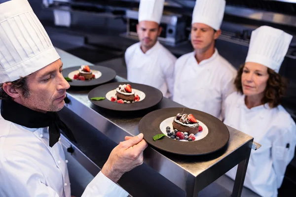 Головний шеф-кухар оглядає десертні тарілки — стокове фото