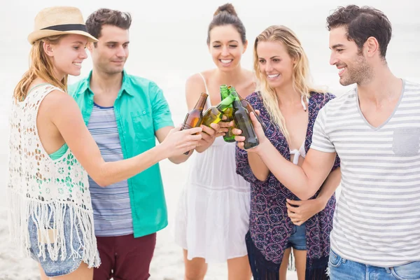 Grupp vänner rosta ölflaskor på stranden — Stockfoto