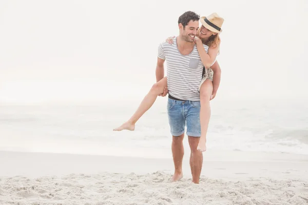 Man tot vrouw geven een piggy terug op het strand — Stockfoto