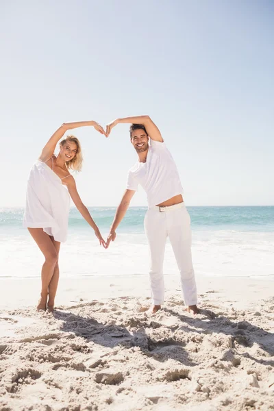 Smiling young couple doing heart shape — Stock Photo, Image