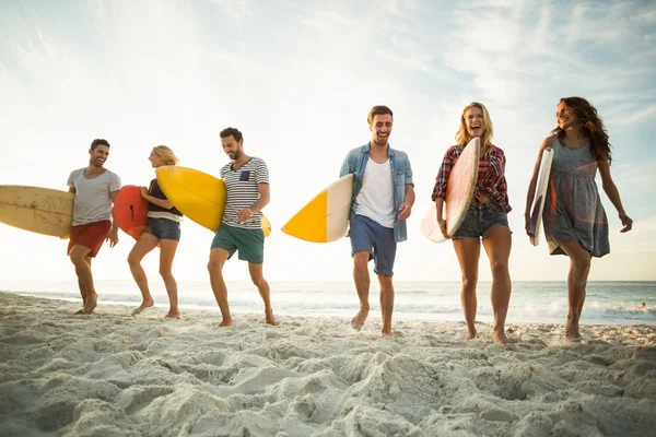 Amigos sosteniendo tabla de surf en la playa — Foto de Stock