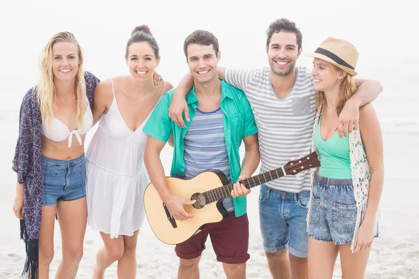 Grupo de amigos de pé na praia com uma guitarra — Fotografia de Stock