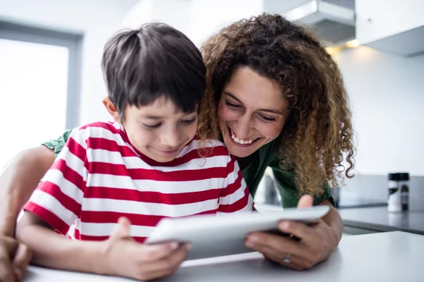 Mãe e filho usando tablet digital na cozinha — Fotografia de Stock