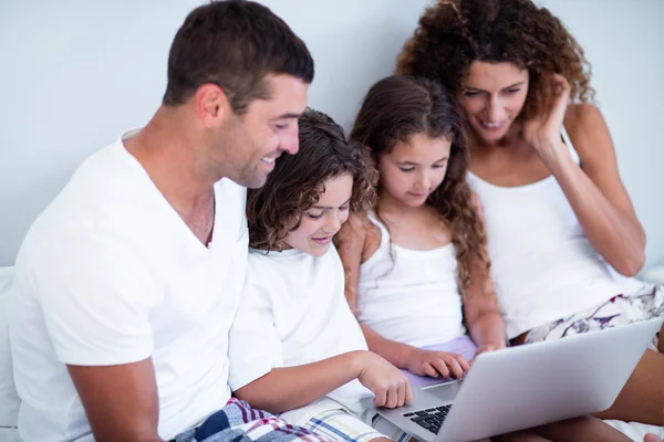 Familie met behulp van laptop samen op bed — Stockfoto