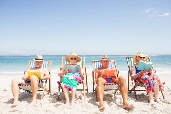 Amis aînés lisant des livres sur chaise de plage — Photo