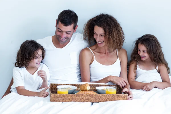 Família sentado com bandeja de pequeno-almoço na cama — Fotografia de Stock