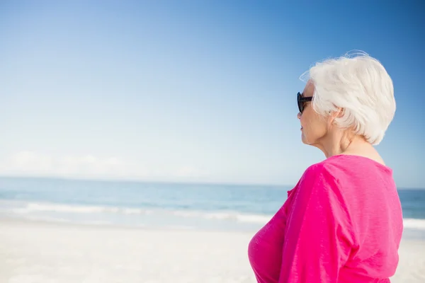 Glückliche Seniorin mit Sonnenbrille blickt aufs Wasser — Stockfoto