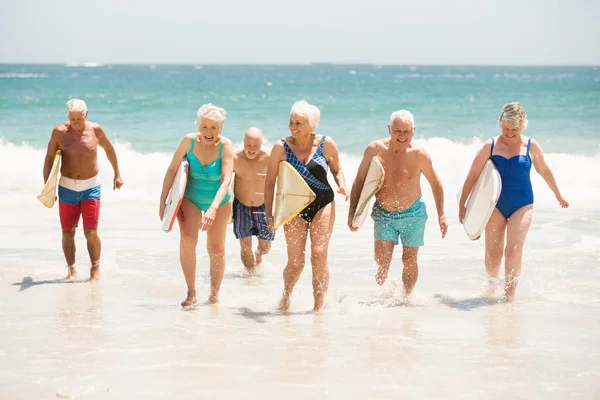 Літні люди, що тримають дошки для серфінгу на пляжі — стокове фото
