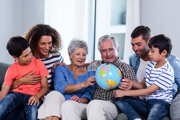 Boldog család egy földgömb, nappaliban nézi — Stock Fotó