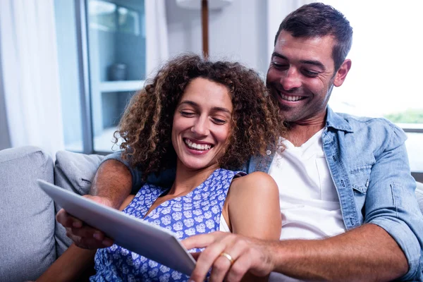 Casal jovem usando um tablet digital no sofá — Fotografia de Stock