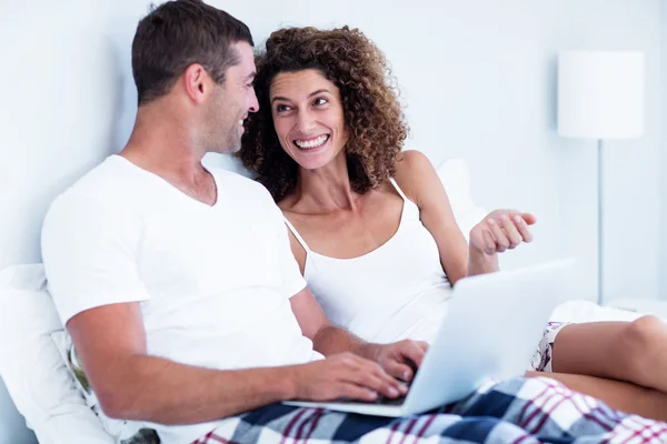Счастливая пара с ноутбуком на кровати — стоковое фото