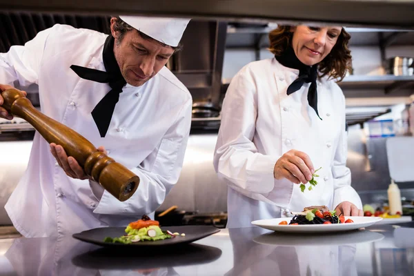 Twee chefs garnituur van de maaltijd op teller — Stockfoto