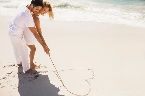 Couple drawing heart on sand — Stock Photo, Image