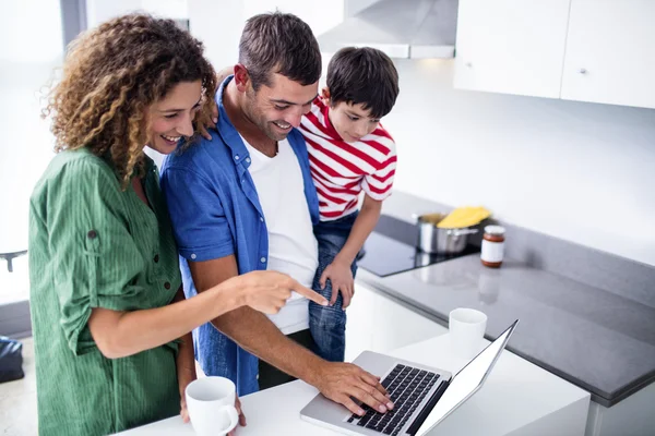 Parents using laptop with son in kitchen — Stock Photo, Image