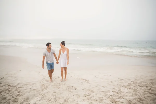 Coppia felice che si tiene per mano e cammina sulla spiaggia — Foto Stock