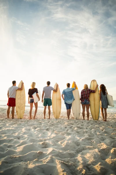 Amigos sosteniendo tabla de surf en la playa —  Fotos de Stock