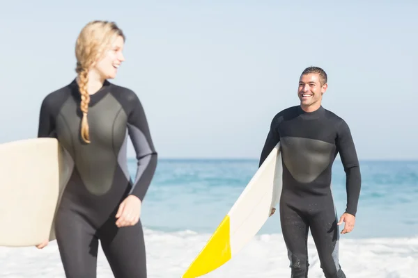 Paar mit Surfbrett am Strand spazieren — Stockfoto