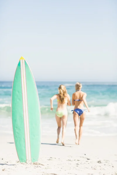 Duas mulheres traseiras correndo na praia — Fotografia de Stock