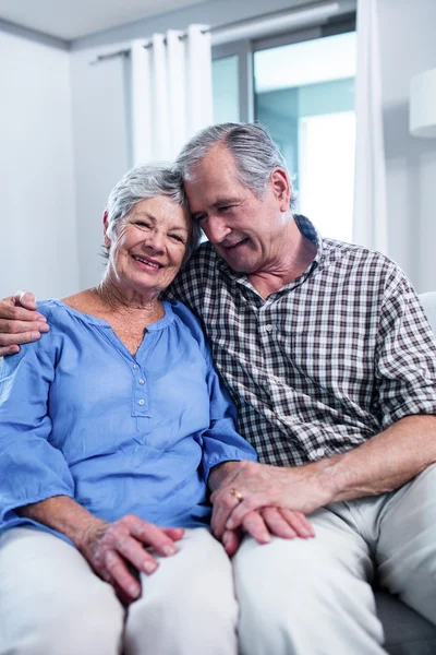 Feliz pareja de ancianos sentados en el sofá y abrazando —  Fotos de Stock
