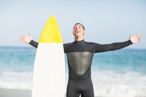 Homem feliz com prancha de surf em pé na praia — Fotografia de Stock