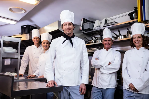 chefs team standing in commercial kitchen