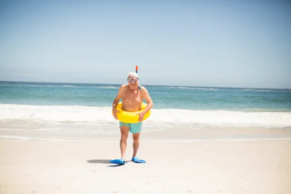 Ανώτερος άνθρωπος με κολύμβηση δακτύλιο και ρακέτες στην παραλία — Φωτογραφία Αρχείου