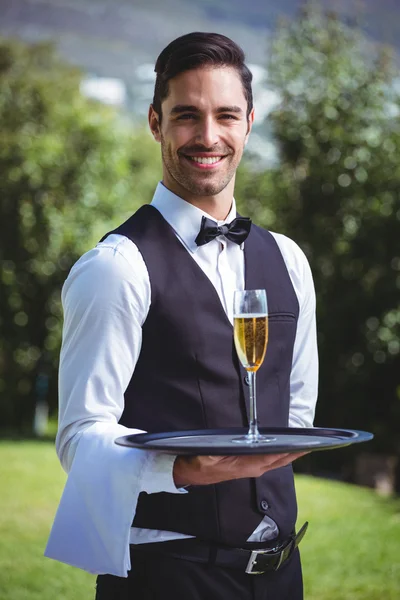 Knappe kelner houden een lade met glas champagne — Stockfoto