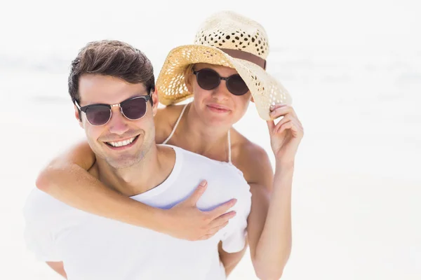 Man tot vrouw geven een piggy terug op het strand — Stockfoto