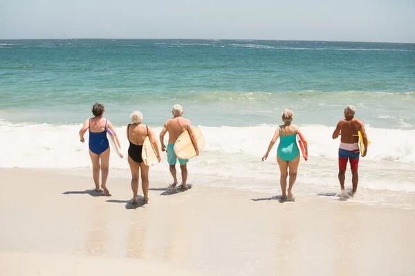 Seniorzy prowadzenie deski surfingowe na plaży — Zdjęcie stockowe