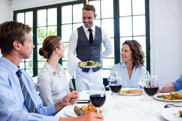 Waiter serving salad to business people Royalty Free Stock Images