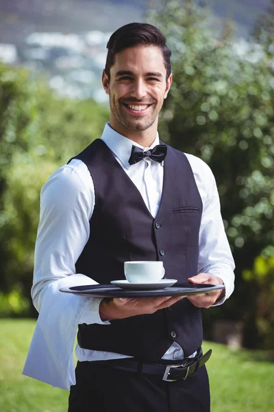 Garçom bonito segurando uma bandeja com xícara de café — Fotografia de Stock